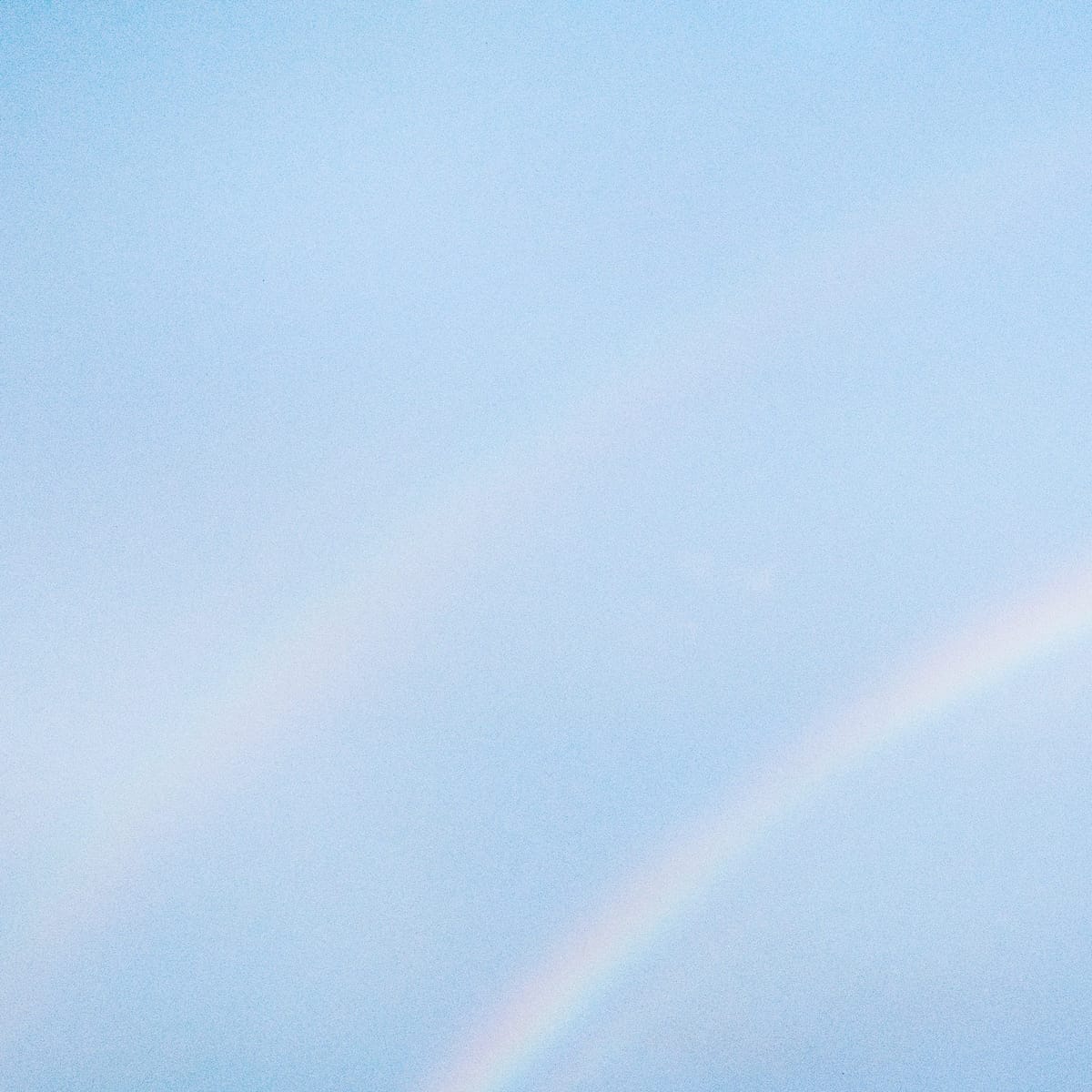 NEVER ENOUGH album cover — light rainbow on a blue sky