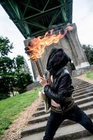 The singer is masked and the guitar is on fire.